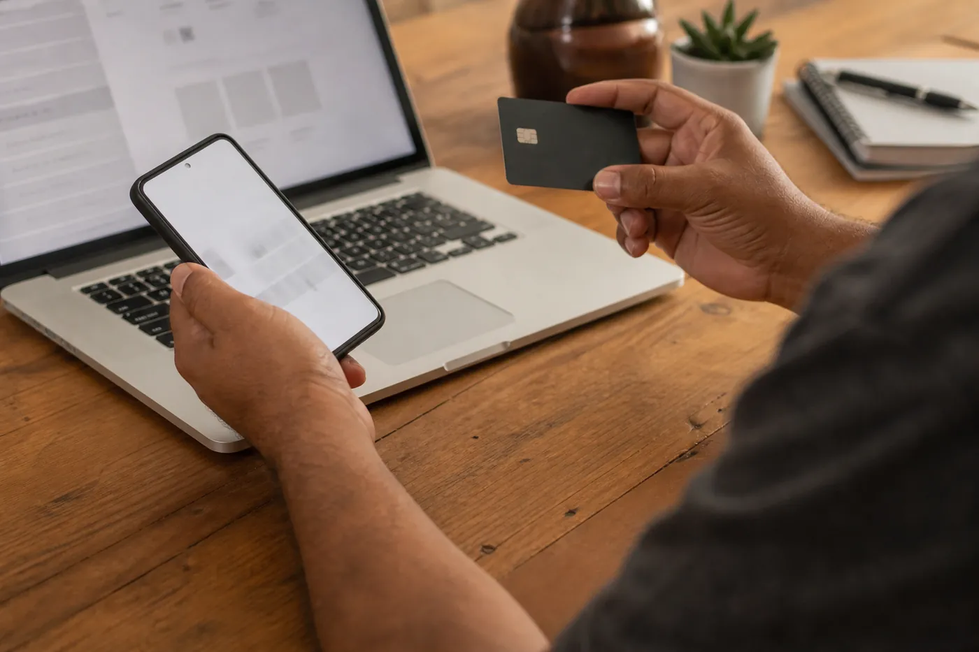 Pessoa prestes a concluir uma compra online, com cartão virado sobre a mesa