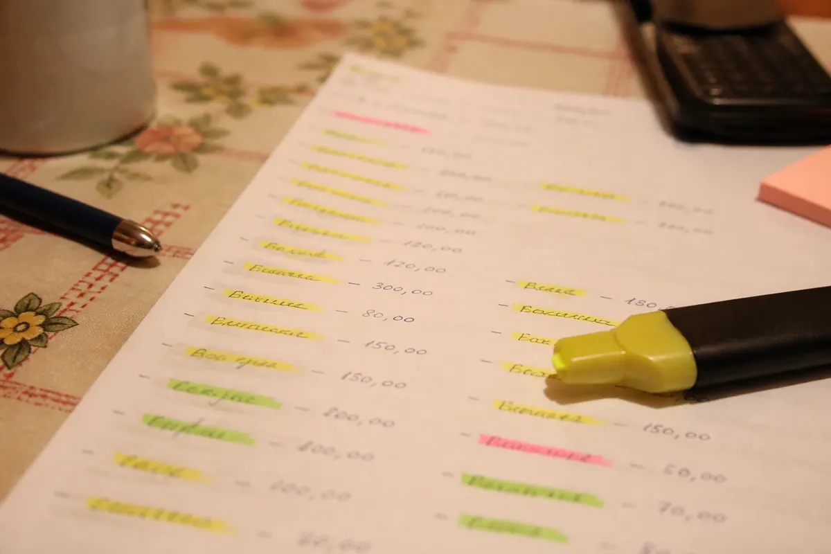 Lista manuscrita de contas e prioridades sobre a mesa